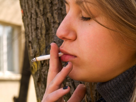 Young student smoking in front of her schoolの写真素材
