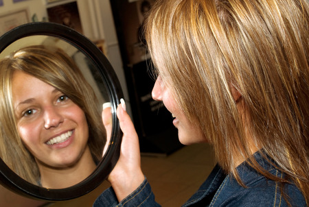 Girl with new hair-style looking herself in the mirrorの写真素材