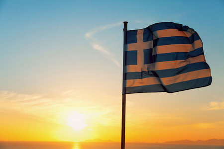 Greek flag waving at sunset in Oia, Santorini, Greeceの写真素材
