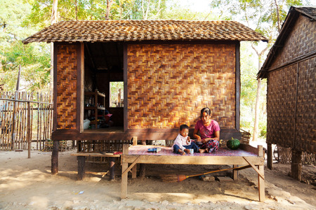 Mandalay, Myanmar - February 28, 2011 : Burmese woman nursering her kid in front of their bamboo temporary house [description:]Burmese people make temporary bamboo houses that could easily be rebuilt somewhere elseのeditorial素材