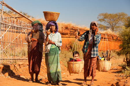 Bagan, Myanmar - February 26, 2011 - 3 women in front of Ananda temple. Two of them are smoking cigars and the other one is holding his child and some firewoodのeditorial素材