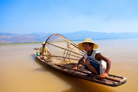 Heho, Myanmar - March 01, 2011 : Father and son fishing in the morning in a traditional long-tail boat in Inle Lake. Fish is an essential part of lake's residents diet.のeditorial素材