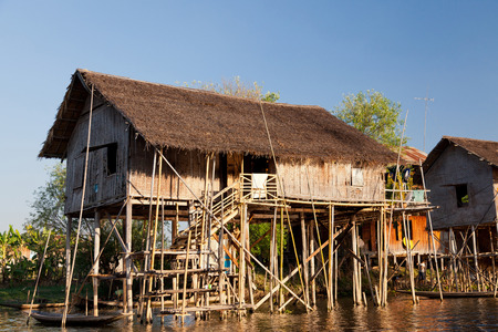 Heho, Myanmar - March 01, 2011 : Ttraditional floating village house on Inle Lake early in the morning. Local people can be seen playing underneath the house near the shore of the lakeのeditorial素材