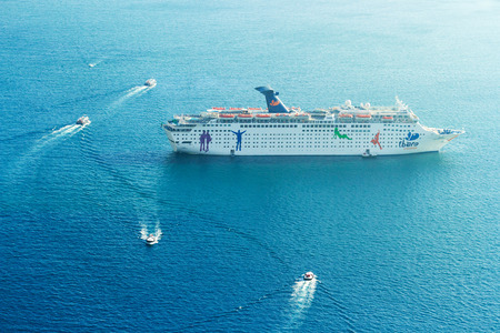 Fira, Greece - May 04, 2012 : Cruise ship disembarking in Santorini with small boatsのeditorial素材