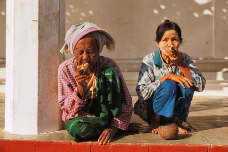 Bagan, Myanmar - February 25, 2011 : Senior Burmese women smoking handmade cigar inside Shwezigon Pagoda in Baganのeditorial素材