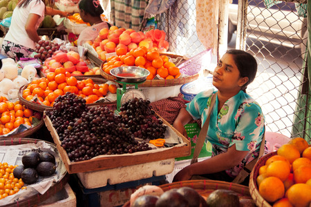 Yangon, Myanmar - February 24, 2011 : Young Burmese woman selling fresh fruits in the street marketのeditorial素材