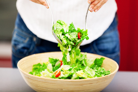 Young woman making salad in the kitchenの写真素材