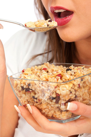 Young woman eating cereal breakfast, looking at camera, isolated on white background with copy spaceの写真素材