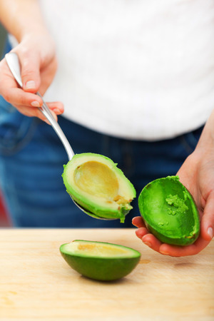 Young woman making salad in the kitchen -  peeling avocadoの写真素材