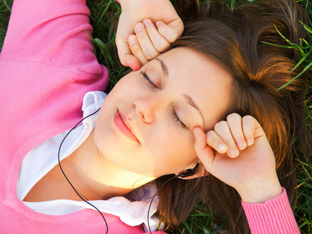 Woman listening to music on the grassの写真素材