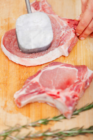 Young woman beating a steak in the kitchenの写真素材