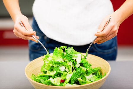 Young woman making salad in the kitchenの写真素材