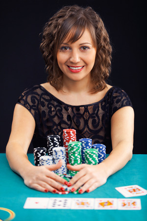 Young woman holding gambling chips on black backgroundの写真素材