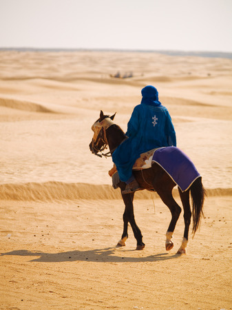 Sahara desert, Tunisia - May 4, 2009: Bedouin riding a horse in the desert in the beginning of the summerのeditorial素材