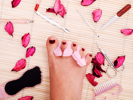 Woman pedicure spa - close up of woman's foot surrounded by rose leavesの写真素材