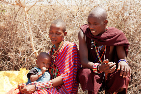 Amboseli, Kenya - February 07, 2012 : Portrait of a young masai family in typical clothing with handmade jewelry with their baby selling jewelry to visitors in masai village in Amboseli national parkのeditorial素材