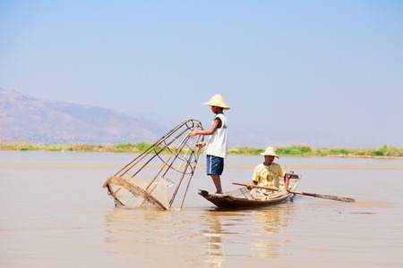 Inle Lake, Myanmar - March 01, 2011 : Father and son fishing in the morning in a traditional long-tail boat in Inle Lake. Fish is an essential part of lake's residents diet.のeditorial素材