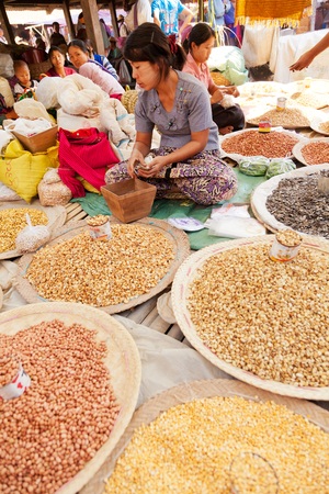 Heho, Myanmar - March 02, 2011 : Young Burmese woman selling nuts and beans at five-day market while sitting on the groundのeditorial素材