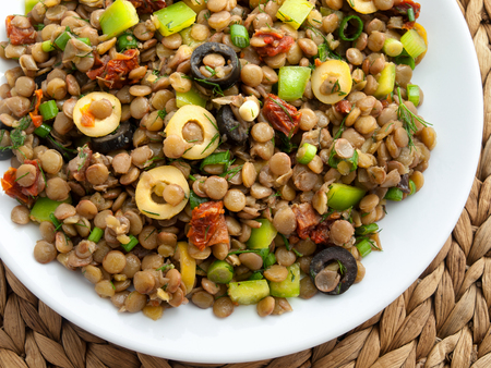 Lentil salad with green peppers, dried tomatoes and olives. Cropped, shot from aboveの写真素材