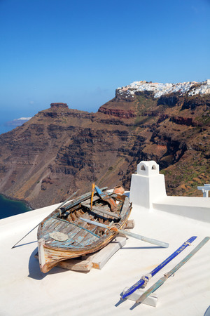 Old boat on the roof of a building in Firostefani, Santorini. Shot at sunrise. The volcano on background. Vertical shotの写真素材