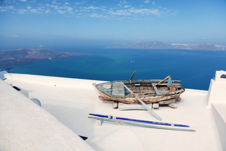 Old boat on the roof of a building in Firostefani, Santorini. Shot at sunrise. The volcano on background. Horizontal shotの写真素材