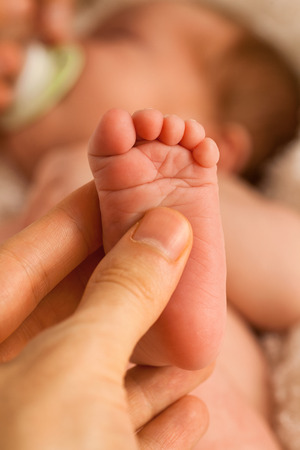 Foot of one week old baby in father\\\'s hand. Close up, vertical shotの写真素材