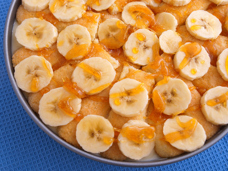 Homemade cake with bananas and caramel in a bowl. Shot on blue backgroundの写真素材