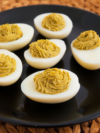 Stuffed eggs with mustard and yolk in a plate. Vertical shotの写真素材