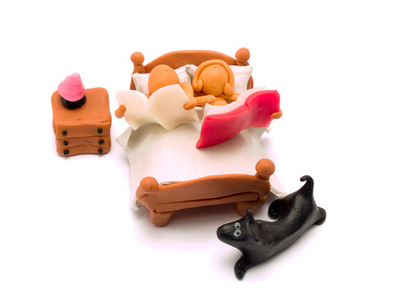 Man and Woman made of plasticine in Bed reading a book and a newspaper with their dogの写真素材