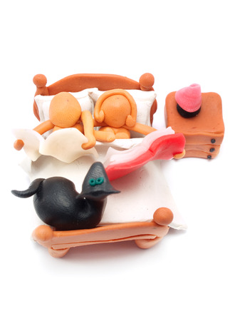 Man and Woman made of plasticine in Bed reading a book and a newspaper with their dogの写真素材