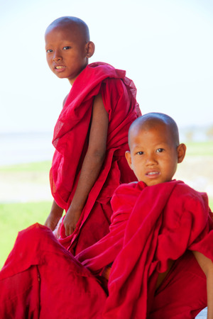 Mandalay, Myanmar - February 28, 2011 - Young Burmese monks in red clothes walking on U Bain Bridgeのeditorial素材
