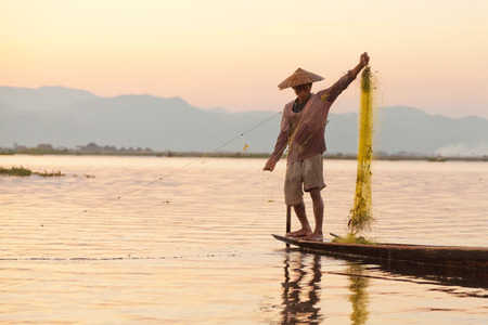 Heho, Myanmar - March 01, 2011 - Man fishing in the evening in a traditional long-tail boat at Inle Lakeのeditorial素材