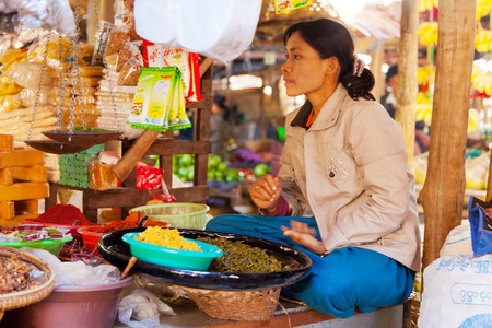 Bagan, Myanmar - February 26, 2011 : Photograph of a middle aged burmese woman selling spices in an open-air market. Typicaly in Bagan the men work on the field while the women sell the production in the market and take care for the children.のeditorial素材