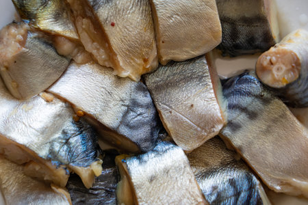Pieces of fresh and delicious homemade pickled herring on a plate close-up