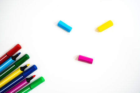 Colorful marker pens with caps removed on white