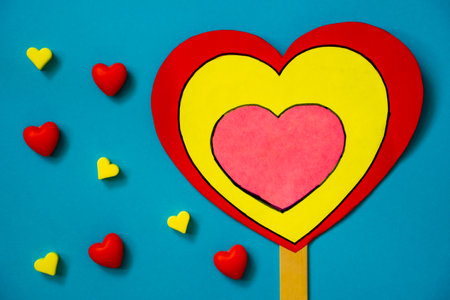 VALENTINE'S DAY background. A large multi-colored heart on a stick, red and yellow silicone hearts a...