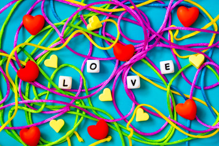 DAY VALENTINE background. Red and yellow silicone hearts, multi-colored laces and the inscription LOVE on a blue backgroundの写真素材