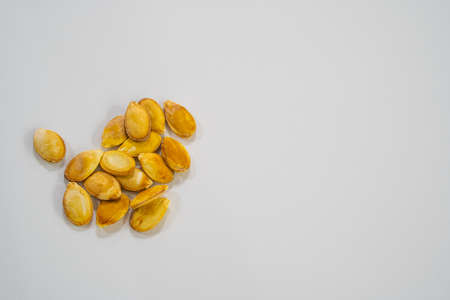 A handful of healthy unpeeled pumpkin seeds on a white background. Healthy and natural food for a happy life.の写真素材