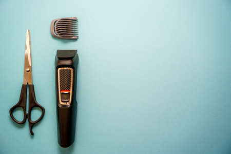 Professional hairdressing tools, hair clipper with attachments and scissors on a blue background. Place for text. Copy spaceの写真素材