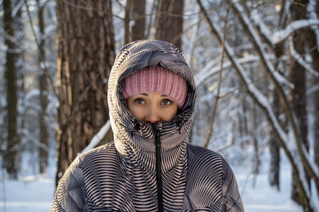 Portrait of a young woman in warm winter clothes in a cold winter forest.の写真素材