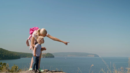 Against the backdrop of a blue cloudless sky, a mother stands with her son on a cape. From the eyes are directed towards the sea at the sailing ships. Mom shows her son the movement of his handの写真素材