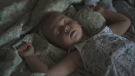 Peaceful carefree adorable baby boy sleeping on the bed in the room. Concept of sound and healthy baby sleep. childcare. happy childhood.の写真素材