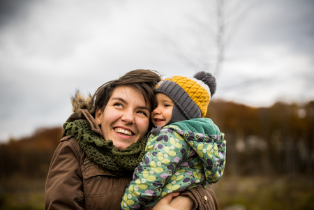 Happy mother and son looking up. Walking in forest in autumn and smileの写真素材