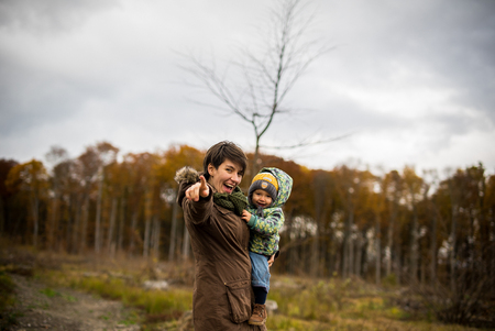 Happy mother and son looking at camera, smile. Walking in forest in autumnの写真素材
