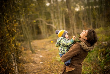 Happy mother and son looking very happy. Walking in forest in autumn and smile.の写真素材