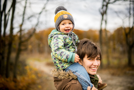 Happy mother and son looking at camera. Walking in forest in autumnの写真素材