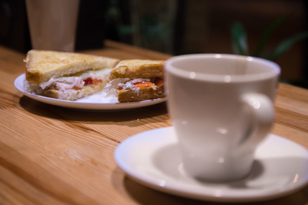 Coffee and sandwich on the table at night or early morning in cafeの写真素材
