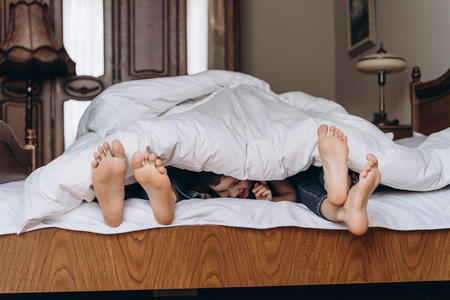 Happy family playing together on bed. Parents spending free time with their son. 4kの写真素材