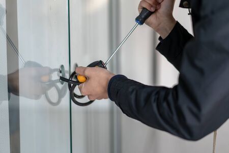 Man using screwdriver to open glass door . Burglar breaking in. Burglary.の写真素材