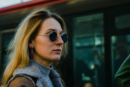 Young woman waiting for tram. European stylish woman wait for her public transport to arrive.